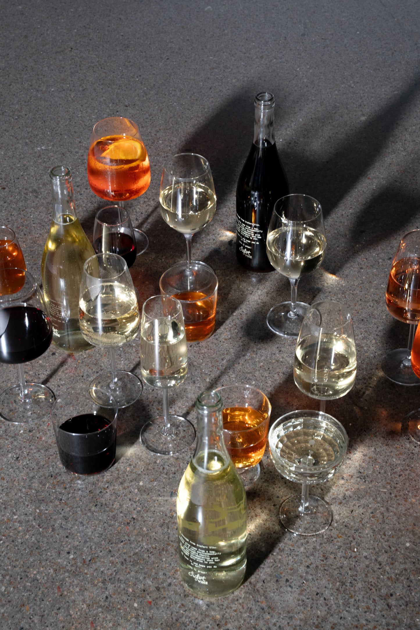 Forskellige vine i glas og flasker fra fustage, står på gulv